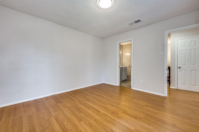 unfurnished room with light hardwood / wood-style flooring and a textured ceiling