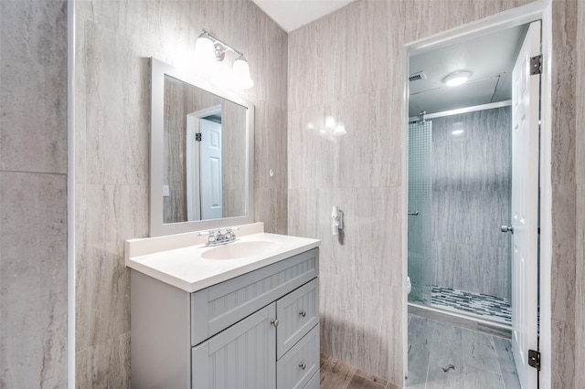 bathroom with tile walls, vanity, and a shower with shower door