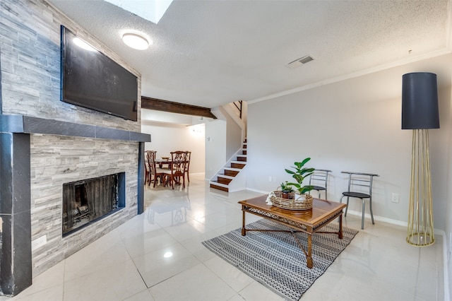 living room featuring crown molding, tile patterned flooring, a skylight, a textured ceiling, and a tiled fireplace