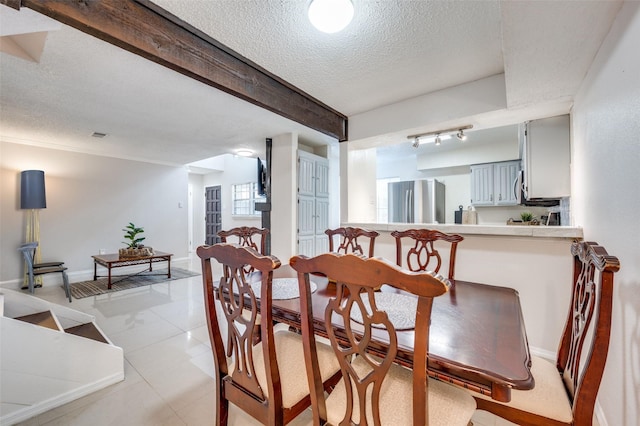 dining space featuring light tile patterned floors, a textured ceiling, and beamed ceiling