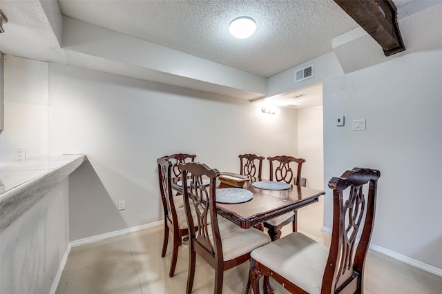 dining space featuring light tile patterned flooring and a textured ceiling