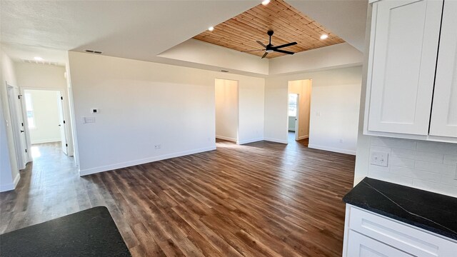 interior space featuring dark hardwood / wood-style flooring, wooden ceiling, ceiling fan, and a tray ceiling