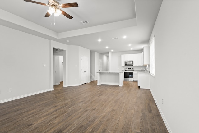 unfurnished living room with dark hardwood / wood-style flooring and ceiling fan