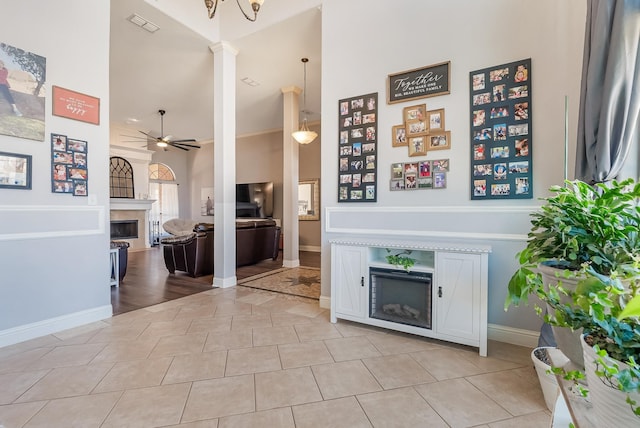 living room featuring light tile patterned flooring, ceiling fan, and ornate columns