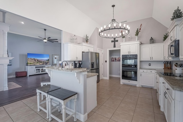 kitchen featuring pendant lighting, light stone countertops, black appliances, a kitchen bar, and kitchen peninsula