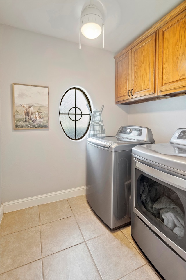 laundry area with cabinets, light tile patterned floors, and washer and clothes dryer