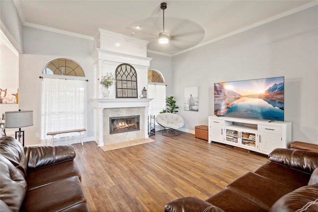 living room with hardwood / wood-style flooring, ceiling fan, a towering ceiling, and crown molding