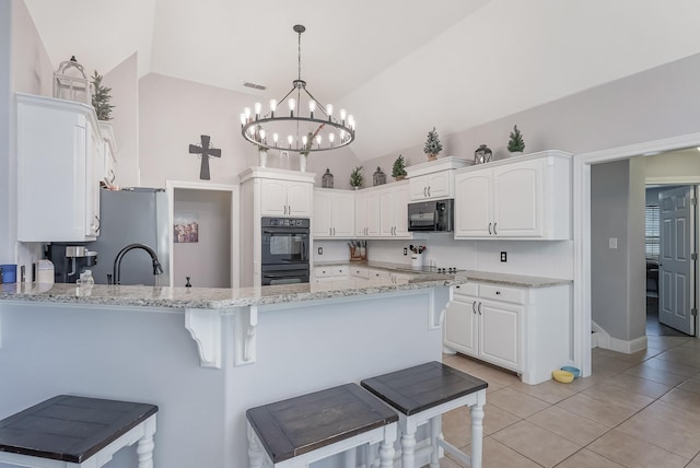 kitchen with white cabinetry, vaulted ceiling, pendant lighting, and black appliances