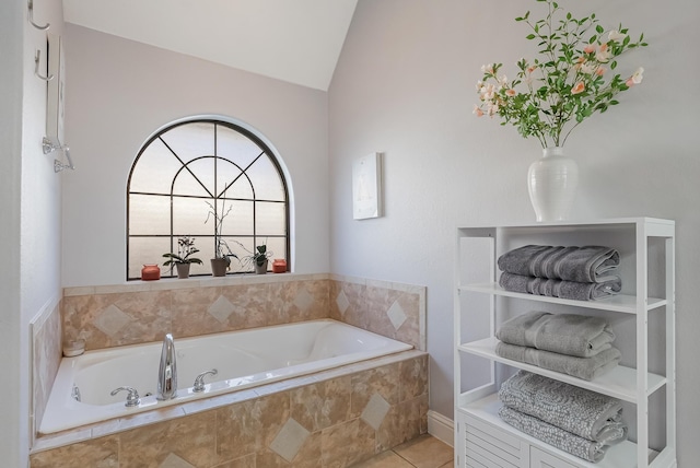 bathroom with a relaxing tiled tub, tile patterned floors, and lofted ceiling