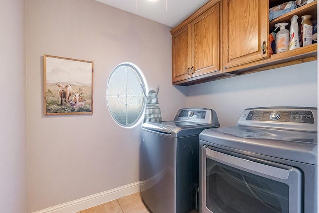 clothes washing area with cabinets, independent washer and dryer, and light tile patterned flooring