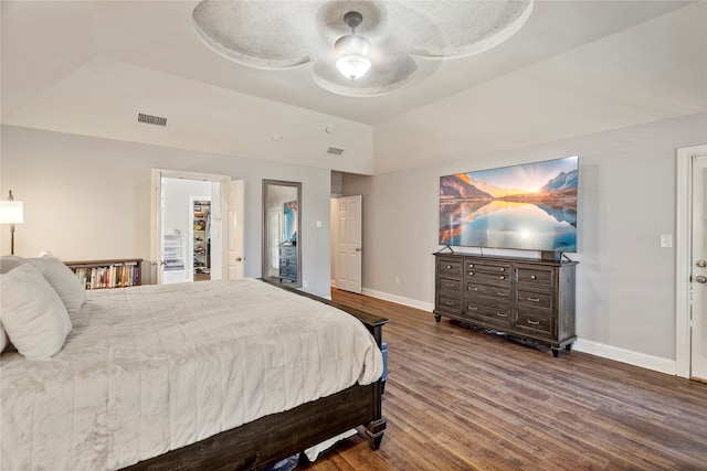 bedroom featuring ceiling fan, a spacious closet, dark wood-type flooring, and a tray ceiling