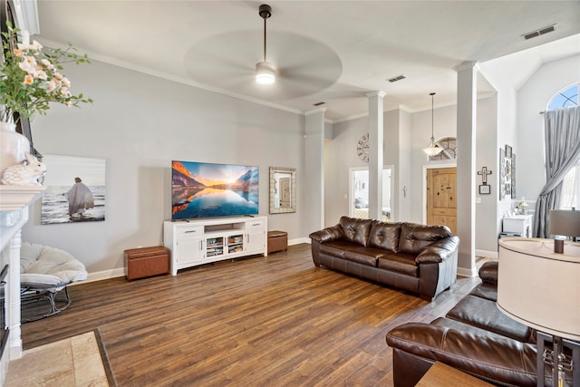 living room with decorative columns, ceiling fan, crown molding, and dark wood-type flooring