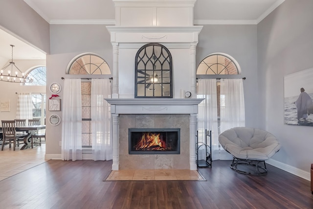 living room featuring a tile fireplace, ornamental molding, hardwood / wood-style floors, and a chandelier