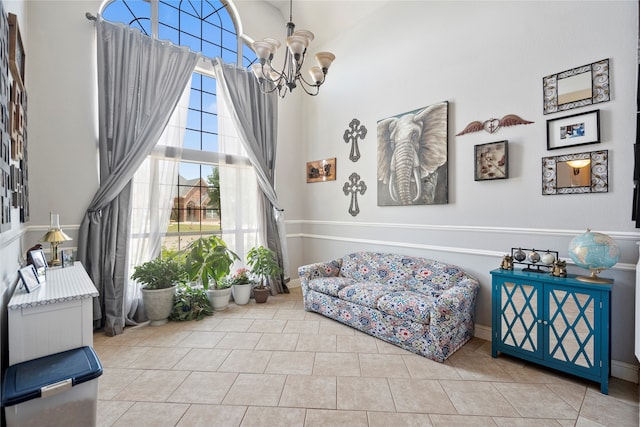 living area featuring tile patterned floors, a towering ceiling, and an inviting chandelier