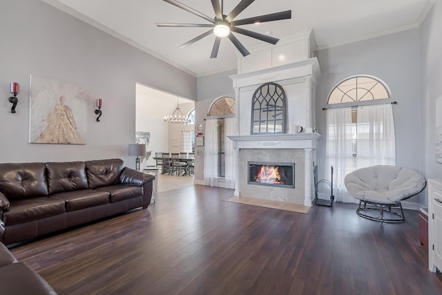 living room featuring dark hardwood / wood-style flooring, crown molding, a chandelier, and a tiled fireplace