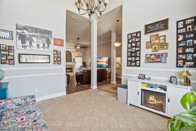 interior space featuring ornate columns, white cabinets, a chandelier, and light tile patterned floors