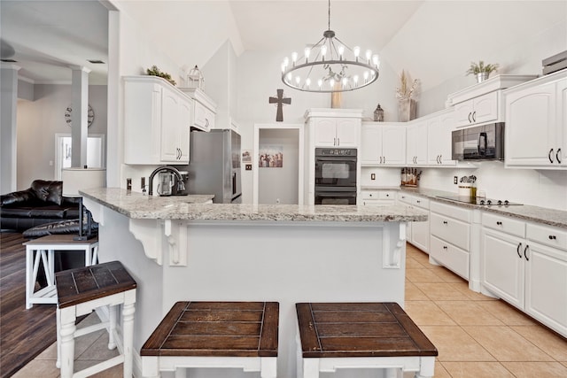 kitchen with light stone countertops, hanging light fixtures, high vaulted ceiling, white cabinets, and black appliances