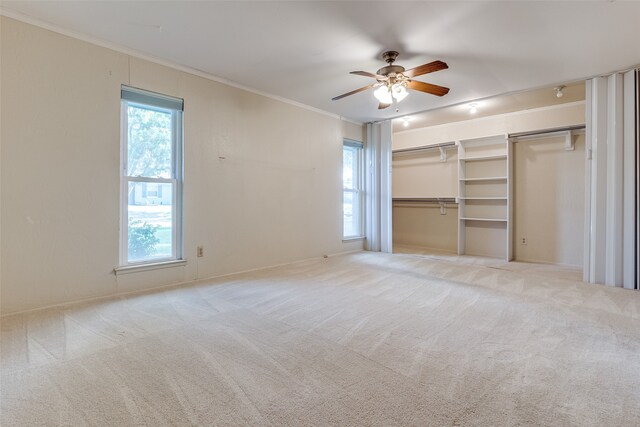 unfurnished living room with ornamental molding, light carpet, a healthy amount of sunlight, and ceiling fan