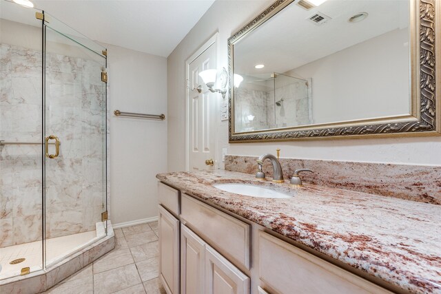 bathroom with a shower with door, vanity, and tile patterned flooring