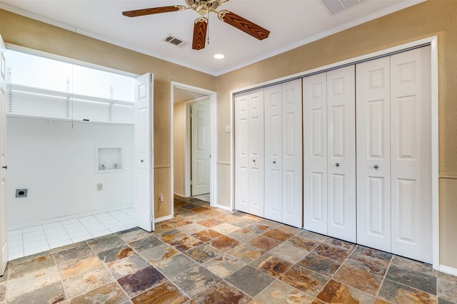 unfurnished bedroom featuring a closet, dark tile patterned floors, ceiling fan, and crown molding