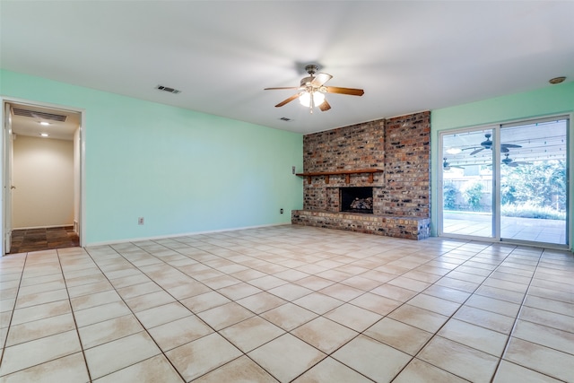 unfurnished living room featuring a brick fireplace, brick wall, light tile patterned floors, and ceiling fan