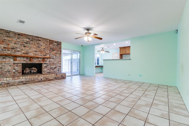 unfurnished living room with light tile patterned flooring, ceiling fan, brick wall, and a brick fireplace