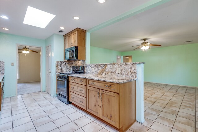 kitchen featuring ceiling fan, tasteful backsplash, black appliances, and a skylight