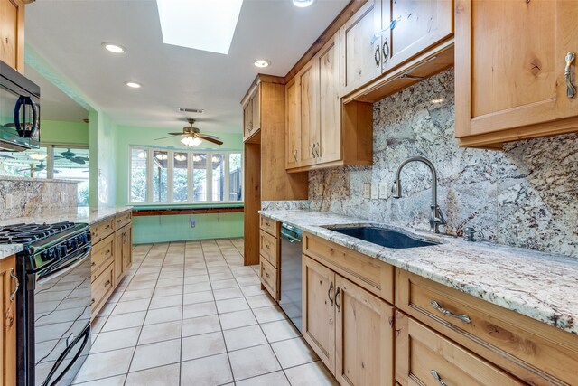 kitchen with tasteful backsplash, black appliances, light tile patterned floors, a skylight, and ceiling fan