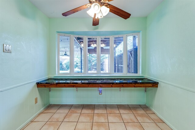 interior space with ceiling fan, a healthy amount of sunlight, and light tile patterned floors