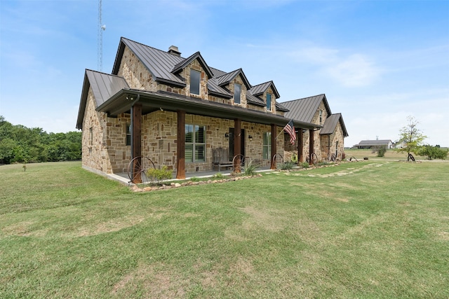 exterior space with metal roof, a yard, a standing seam roof, and stone siding