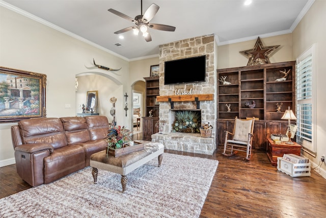 living room featuring dark hardwood / wood-style floors, ceiling fan, crown molding, and a fireplace