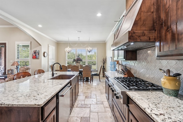 kitchen featuring light stone countertops, stainless steel appliances, sink, a center island with sink, and a chandelier