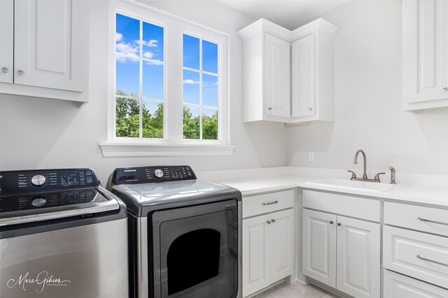 clothes washing area featuring sink, cabinets, and independent washer and dryer