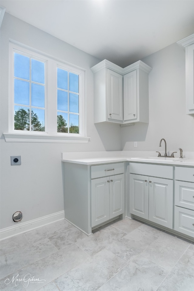 laundry area with electric dryer hookup, sink, and cabinets