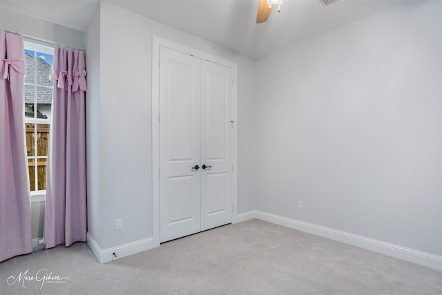 unfurnished bedroom with ceiling fan, light colored carpet, and a closet