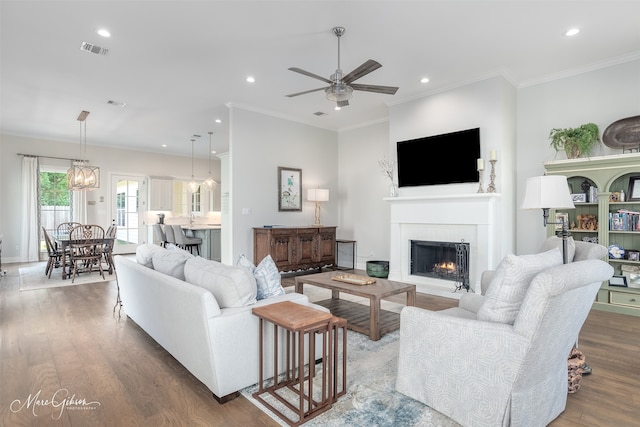 living room with dark hardwood / wood-style floors, sink, ornamental molding, and ceiling fan with notable chandelier