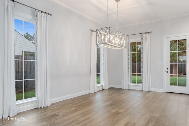 unfurnished dining area with a chandelier, crown molding, a healthy amount of sunlight, and light wood-type flooring