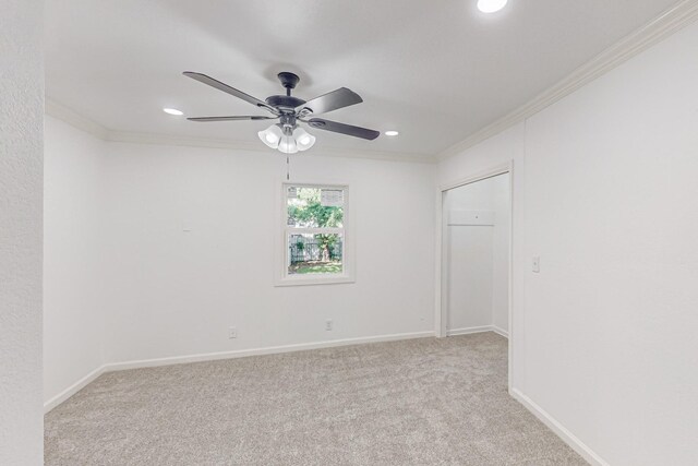 unfurnished room with crown molding, light colored carpet, and ceiling fan