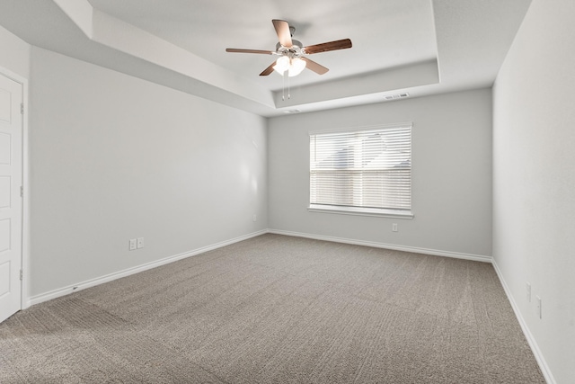 carpeted empty room with a tray ceiling and ceiling fan