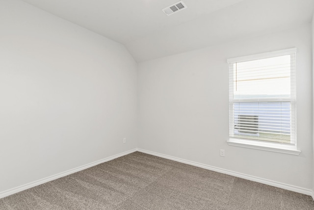 empty room with carpet floors and vaulted ceiling