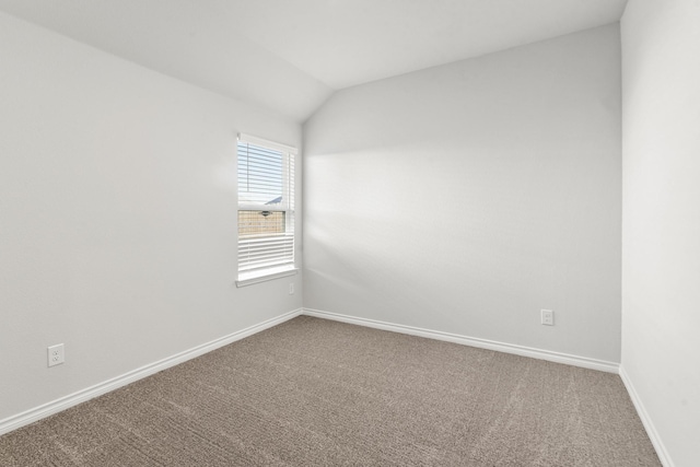 unfurnished room with carpet flooring and vaulted ceiling