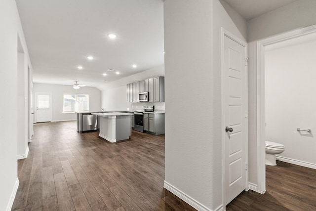 kitchen with appliances with stainless steel finishes, dark hardwood / wood-style flooring, ceiling fan, a center island, and gray cabinets