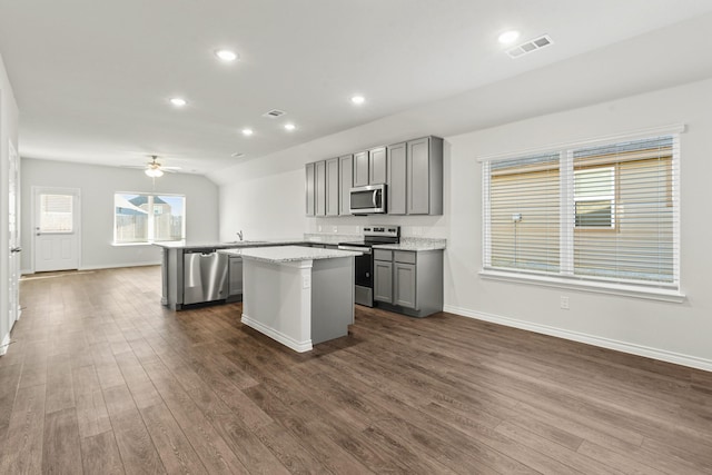 kitchen with dark hardwood / wood-style flooring, stainless steel appliances, light stone counters, and gray cabinetry