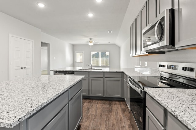 kitchen with light stone countertops, stainless steel appliances, ceiling fan, dark wood-type flooring, and sink