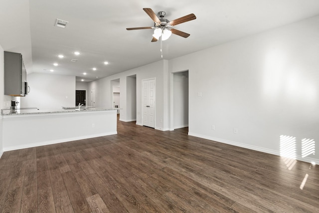 unfurnished living room featuring dark wood-type flooring and ceiling fan