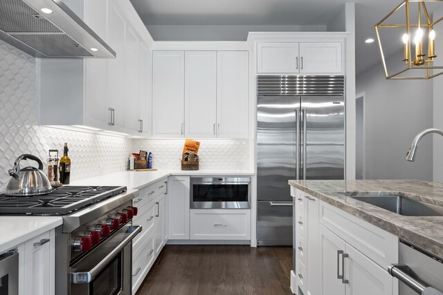 kitchen featuring decorative light fixtures, white cabinets, wall chimney exhaust hood, dark hardwood / wood-style floors, and high quality appliances