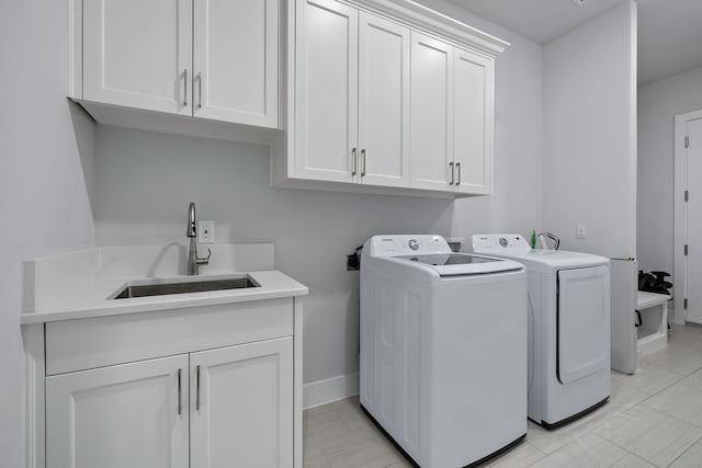 clothes washing area with cabinets, sink, and washer and clothes dryer