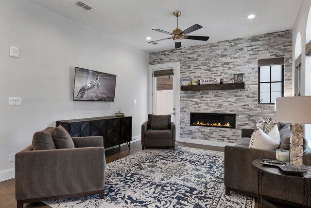 living room with a fireplace, dark wood-type flooring, and ceiling fan