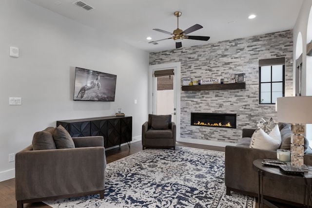 living room with dark hardwood / wood-style floors, a large fireplace, and ceiling fan