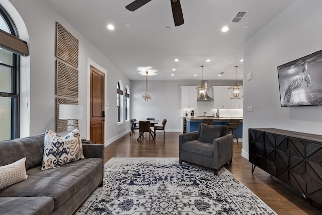 living room featuring dark hardwood / wood-style floors and ceiling fan with notable chandelier